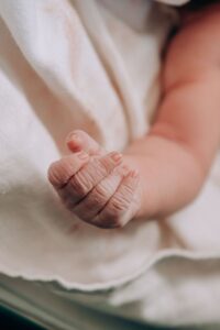 Parent holding a premature newborn's hand after a premature birth