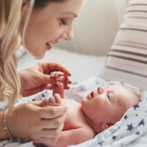 Parent bonding with a newborn wrapped in a soft blanket during gentle interaction and eye contact
